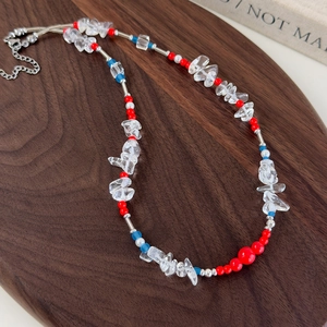 Detail of colorful irregular glass beads and silver metal chain on a wood tray