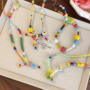Set di collane di perline colorate a fiori e stelle su vassoio portagioie elegante