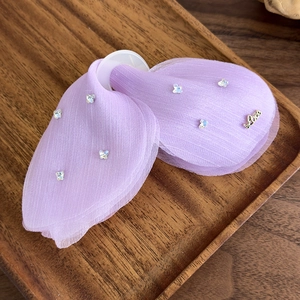 Détail d'une pince à cheveux papillon en tulle violet avec strass et décoration dorée Love