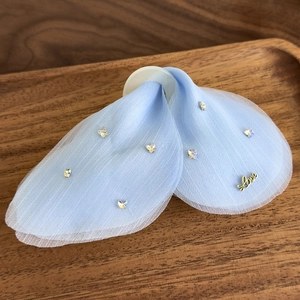 Détail de la pince à cheveux en tulle bleu clair avec strass et breloque Love dorée