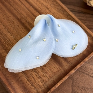 Détail de la pince à cheveux en tulle bleu clair avec cristaux papillons et breloque Love