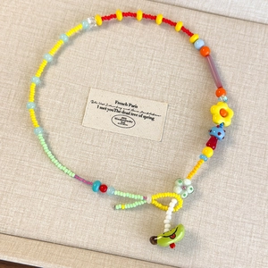 Dettaglio della collana di perline fatta a mano con fiori colorati e ciondoli a fungo