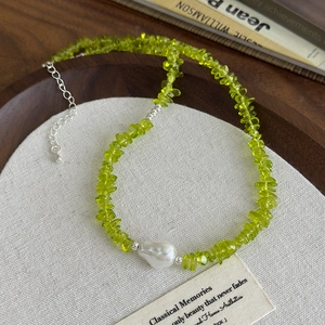 Baroque pearl and green crushed stone necklace on a vintage linen background