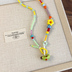 Dettaglio della collana di perline colorate con ciondoli a fiori e funghi sul vassoio