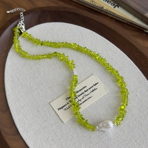 Olive green stone necklace with baroque pearl on white linen display in wooden tray