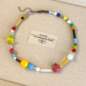 Collana di perline colorate con fiori e chiusura a moschettone su sfondo beige