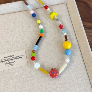 Dettaglio di una collana di perline colorate fatta a mano con fiori e ciondoli