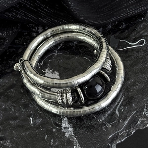 Detail of three-layer silver elastic bracelet with black stone and retro carvings