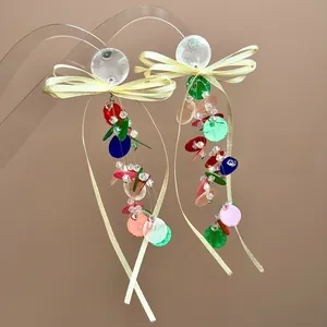 Detail of colorful sequin tassel earrings with yellow bow and translucent round stud