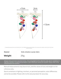 Detailed view of long shell drop earrings with white silk bows and 12cm length specifications