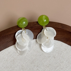 Gros plan de boucles d'oreilles d'été en résine vert avocat avec disques de nacre