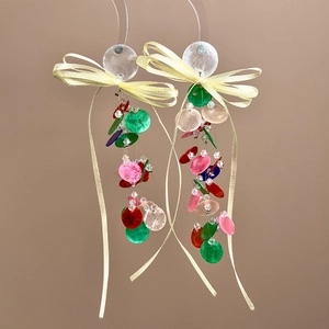Detail of colorful tassel earrings with ribbon bows and iridescent round shell discs
