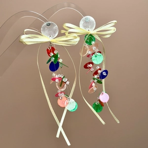 Close-up of colorful round sequins and yellow ribbon bow on long tassel earrings