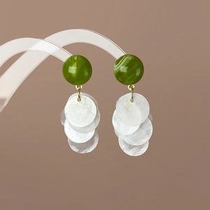 Détail d'une perle marbrée vert avocat et de pétales de coquillage blanc sur boucle d'oreille