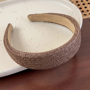Detailed close-up of a brown woven straw wide headband featuring a soft beige fabric lining
