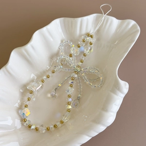 Macro detail of beaded phone charm with iridescent crystals and golden accents