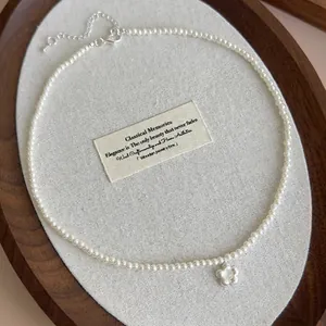 Elegant pearl necklace featuring a brushed mother-of-pearl flower pendant on linen background