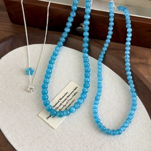 Detailed close-up of blue cat eye stone beads and silver floral pendant necklace