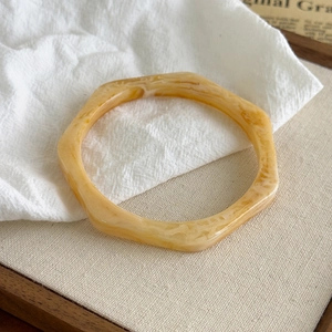Detail eines Bernstein-Resin-Armreifs mit Marmortextur auf elegantem weißem Stoff