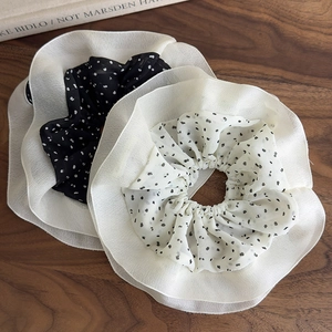 Oversized polka dot chiffon scrunchies in black and white set on a wooden background