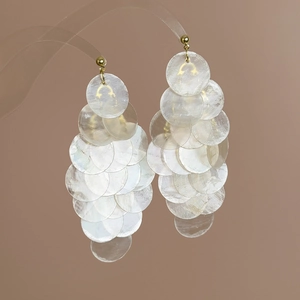 Detail of mint green iridescent shell discs with golden spherical stud earrings
