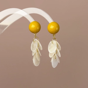 Détail de boucles d'oreilles en coquillage vert avocat et blanc sur support acrylique