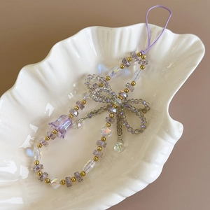 Detailed shot of purple beaded phone strap with bow and lily of the valley charm
