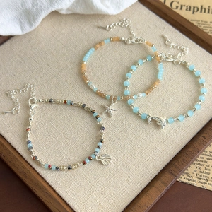 Detail of beaded bracelets with starfish and shell charms on a rustic tray