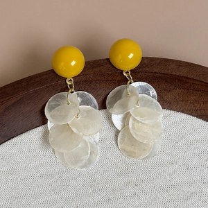 Détail de boucles d'oreilles pendantes en coquillage suspendues sur un bol en bois
