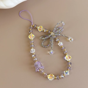 Detail of beaded phone charm with purple tulip and crystal beads on beige background