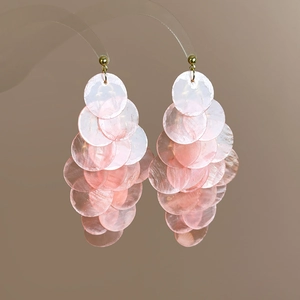 Detailed view of pink shell layered tassel earrings with iridescent mother of pearl glow