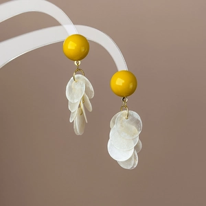 Détail d'un clou en résine jaune et de disques en nacre sur un support à bijoux