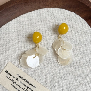 Détail macro de boucles d'oreilles en coquillage vert avocat sur lin blanc