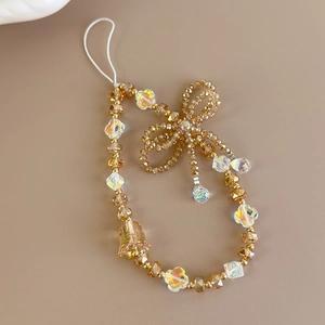 Macro detail of champagne and white crystal beaded phone lanyard with a bow charm
