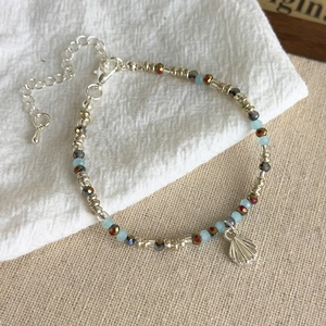 Detail of blue starfish bead bracelet with silver shell charm and adjustable lobster clasp