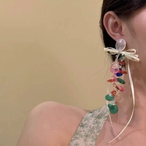 Colorful resin disc drop earrings with white ribbon bow on a model for sweet vacation style