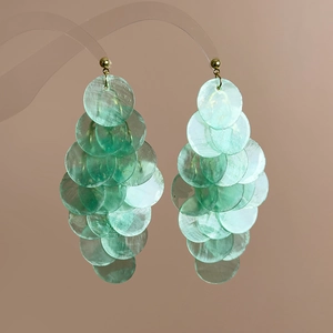 Detail of mint green shell earrings with layered circular mother-of-pearl discs and gold hooks