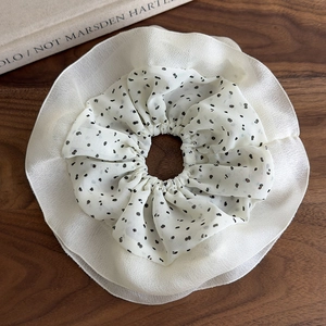 Close-up of a double-layered chiffon scrunchie with classic black polka dots and white ruffles