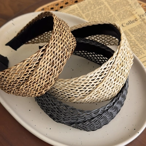 Three bohemian woven headbands in brown, cream, and black colors on a ceramic tray