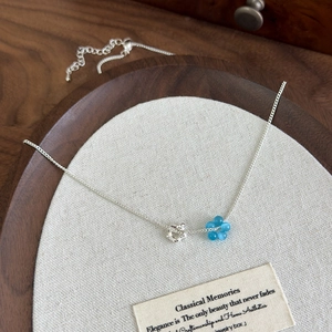 Detail of silver necklace with blue cat eye stone flower and hollow star charms