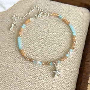 Close-up of ocean-style beaded bracelet with silver starfish charm and white pearls