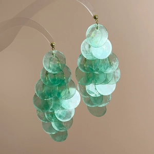 Detailed macro view of cascading mint green shell discs on golden bohemian earrings