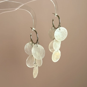 Detailed close-up of bohemian silver drop earrings with translucent seashell disks