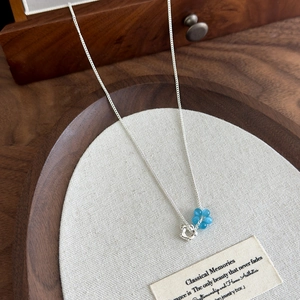 Close-up of blue cat eye stone flower pendant necklace on elegant linen cushion