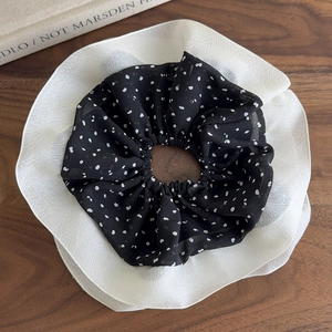 Detail of oversized chiffon scrunchie with black polka dots and white ruffled edge