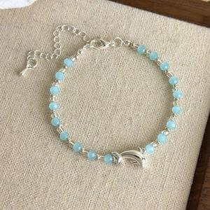 Detailed shot of blue beaded bracelet with silver dolphin charm and adjustable lobster clasp