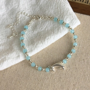 Detailed macro of ocean-style beaded bracelet with blue glass beads and silver dolphin charm