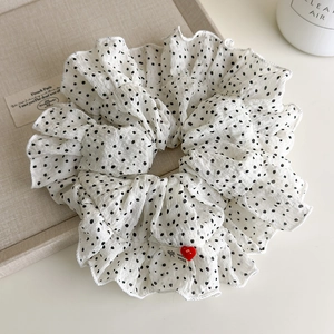 Macro detail of polka dot hair scrunchie with red heart charm and hand made label