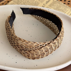 Detailed close-up of woven straw headband featuring brown crisscross textures and inner lining