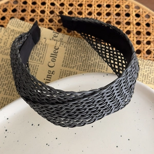 Detailed close-up of a wide black straw braided headband with an intricate mesh texture